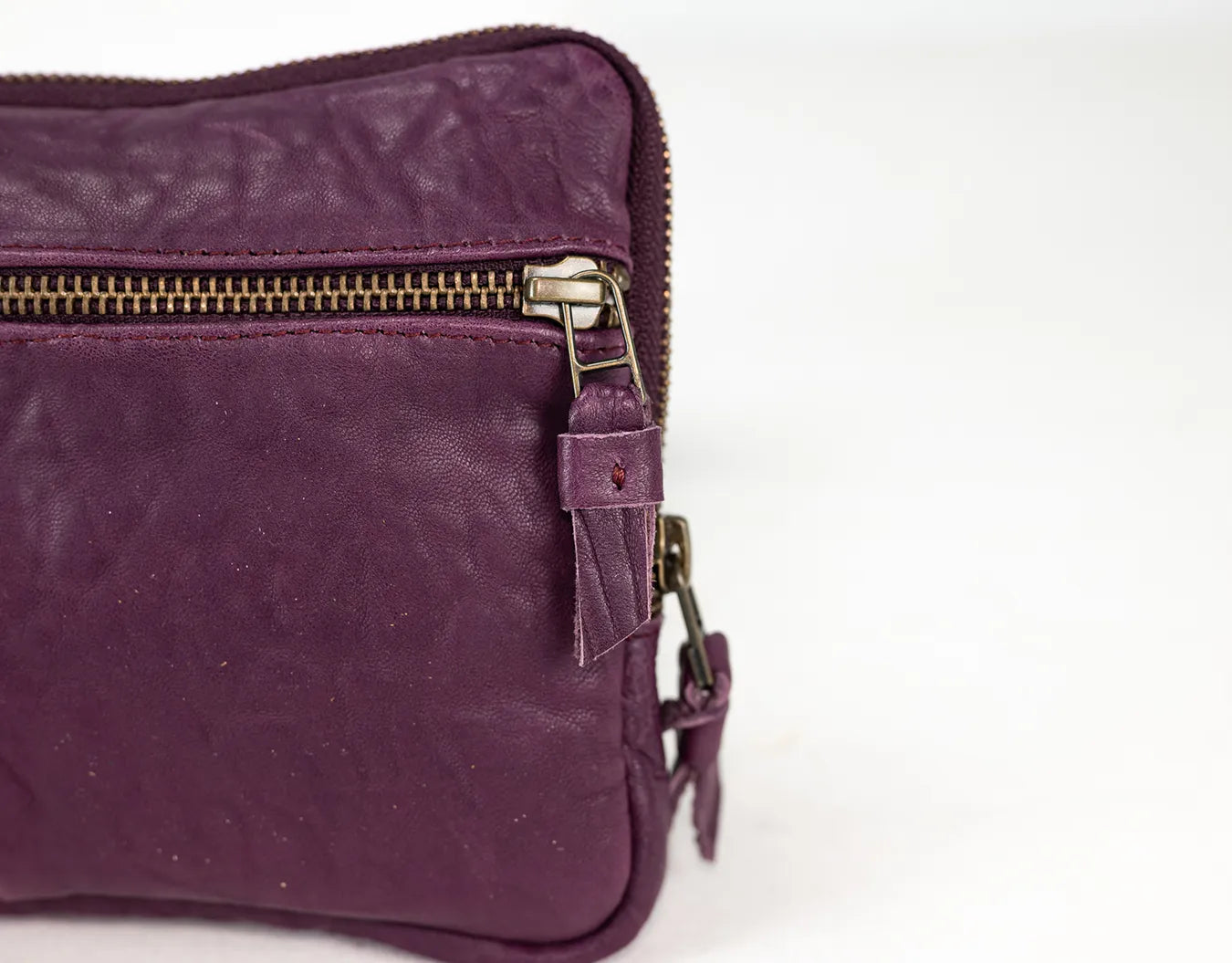 Purple leather bag with gold zipper on a white background