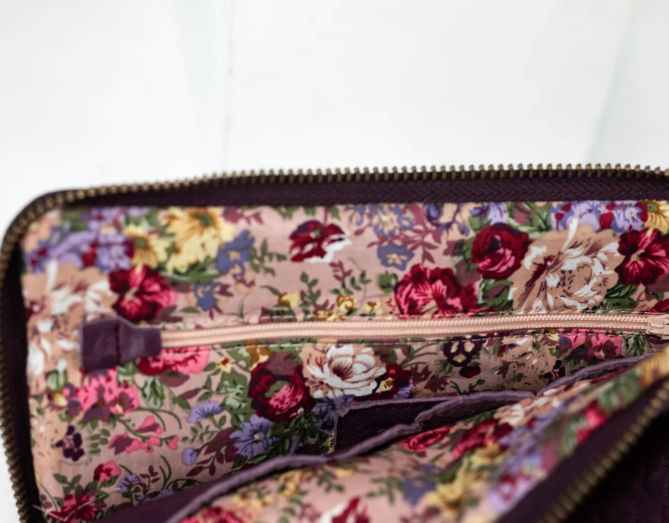 Purple leather bag with a gold zipper on a white background