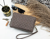Brown quilted clutch bag on a white surface with sunglasses and other accessories.