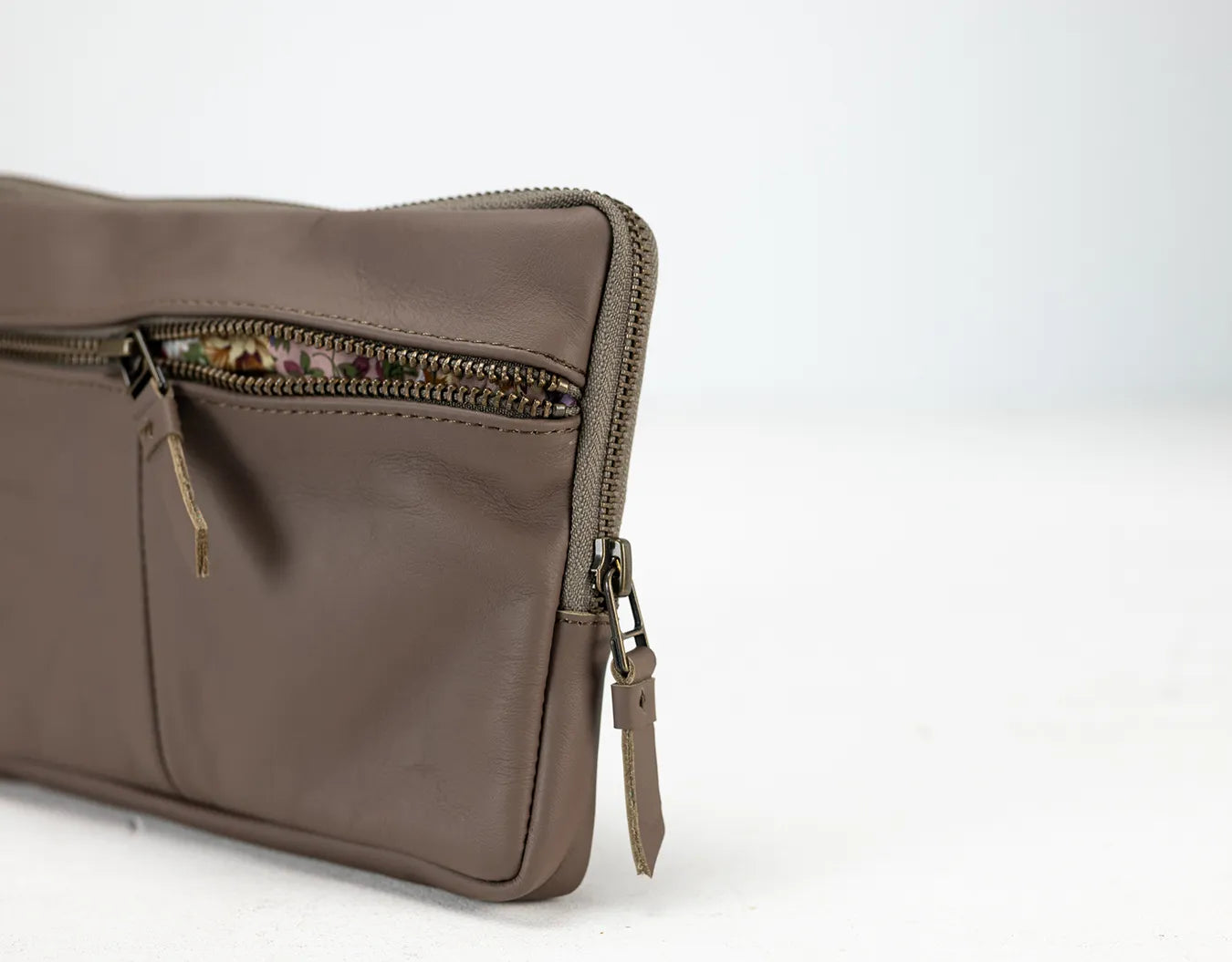 Brown leather clutch bag with zippers on a white background