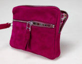 Pink suede handbag with a zipper on a light gray background
