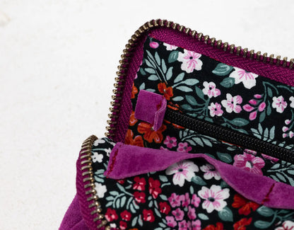Floral-patterned bag with a purple zipper on a light background