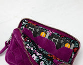 Purple wallet with floral pattern open to reveal cards on a white background