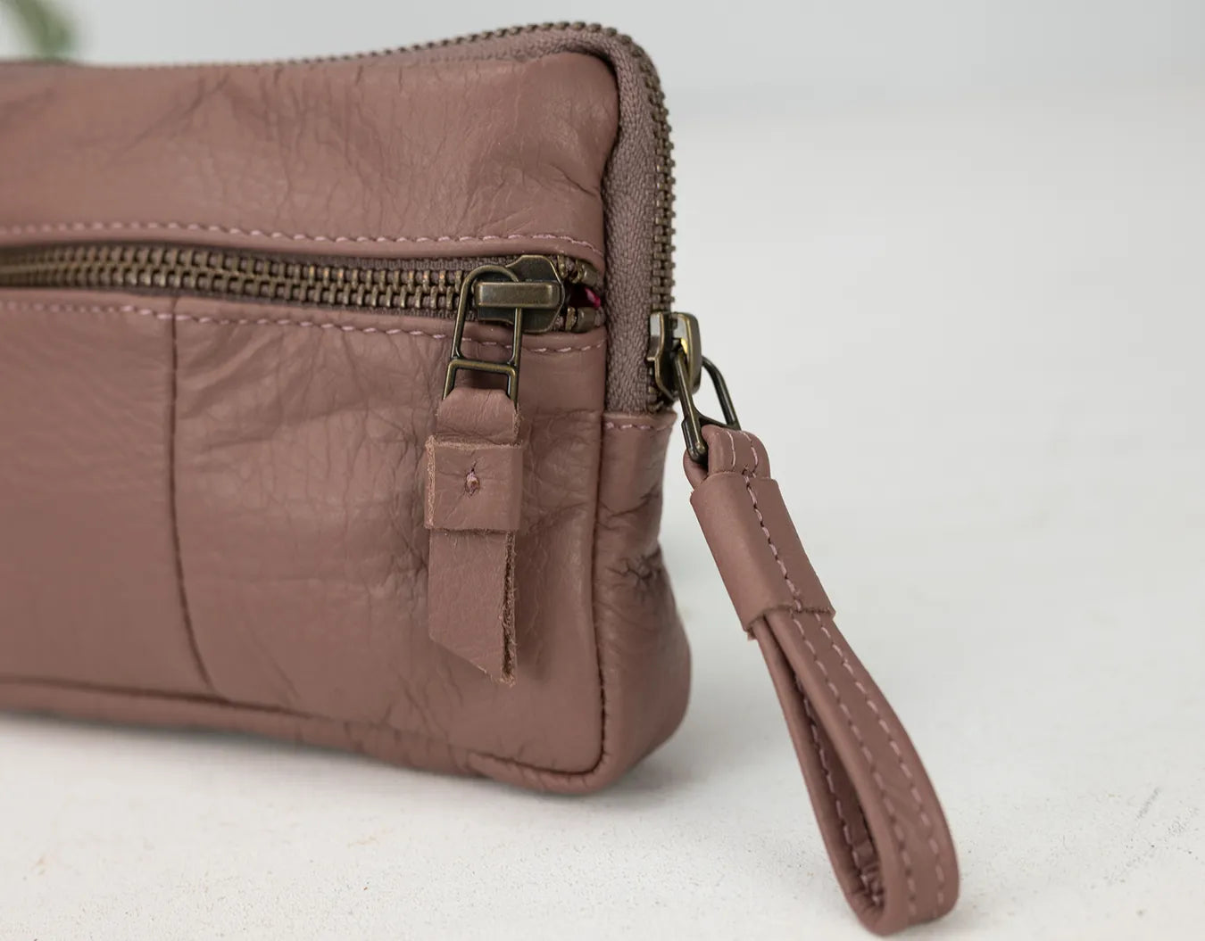 old rose leather clutch with a strap on a white background