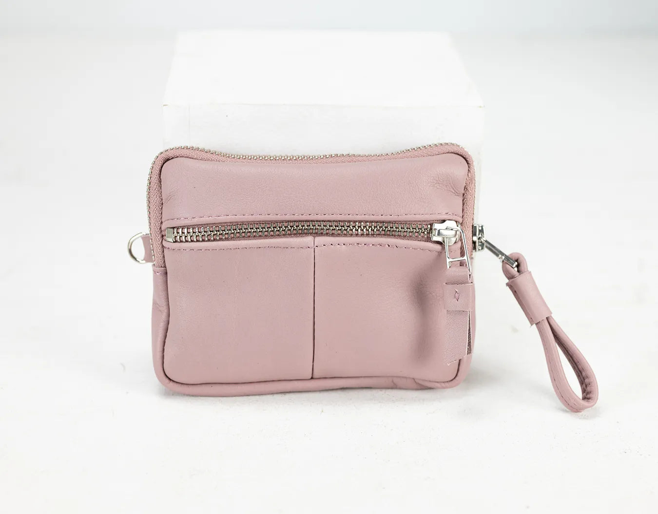 Pink wristlet with a zipper on a white background
