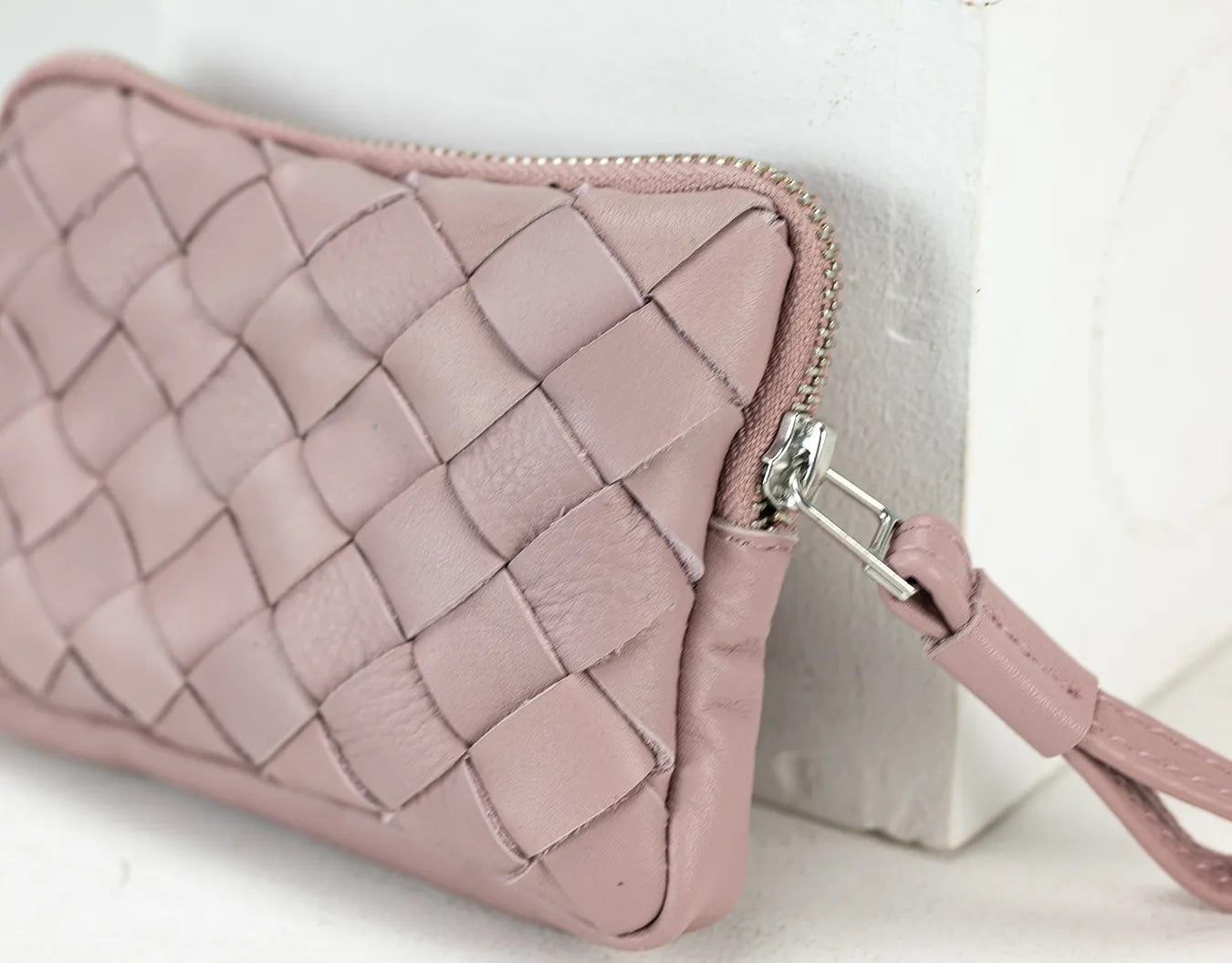 Pink quilted wallet with a strap on a light background