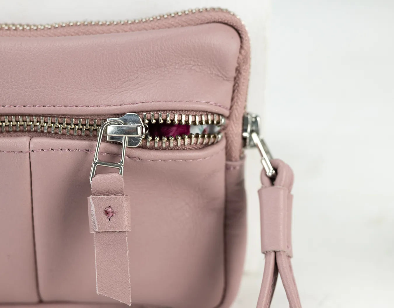 Pink leather handbag with a strap on a light background