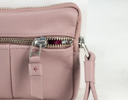 Pink leather handbag with a strap on a light background