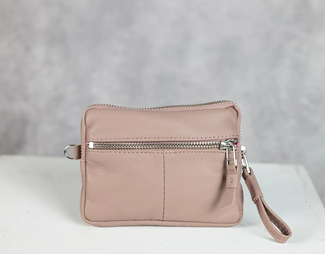 Pink wristlet with a zipper on a light gray background