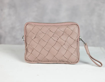 Pink woven clutch bag on a white surface with a gray background