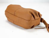 Brown leather bag with a strap on a white background