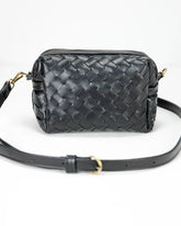 Black woven handbag with a strap on a white background