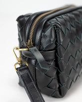 Black woven leather handbag with gold zipper and clasp on a white background