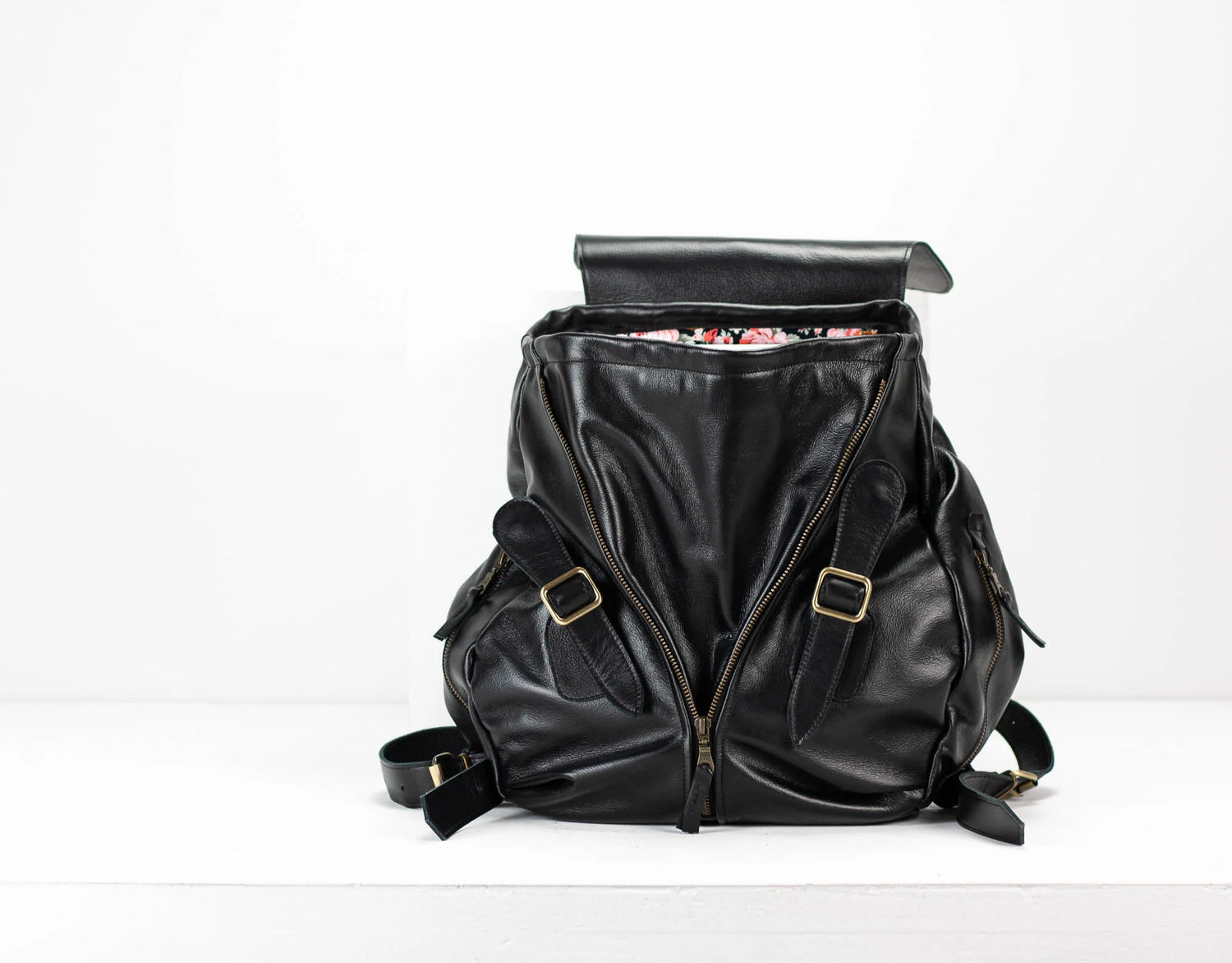 Black leather backpack with gold buckles on a white background