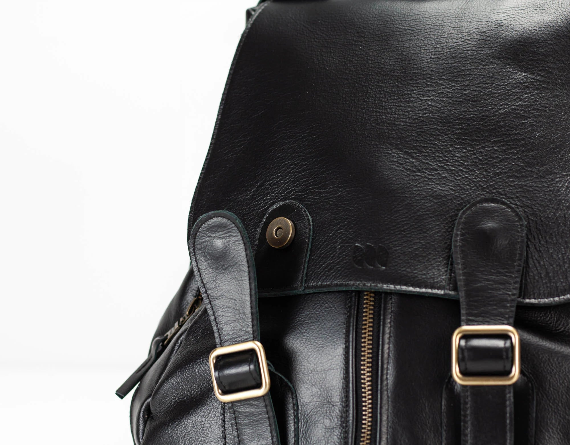 Close-up of a black leather backpack with gold buckles on a white background
