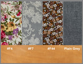 Fabric swatches with floral, patterned, and plain designs on a brown bar with color codes and text.