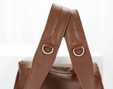 Brown leather bag with gold rings on a white background