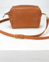Brown leather bag with a strap on a white background