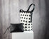 Black and white woven handbag with a matching clutch on a gray background