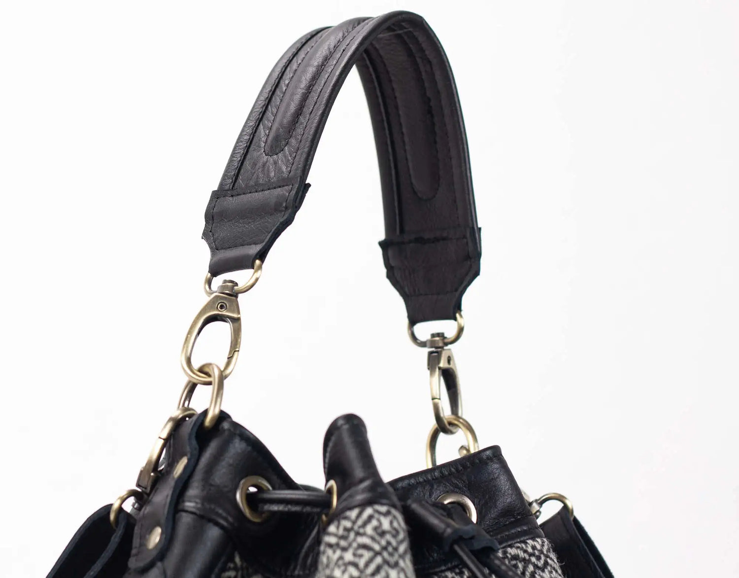 Close-up of a black leather handbag with a strap on a white background