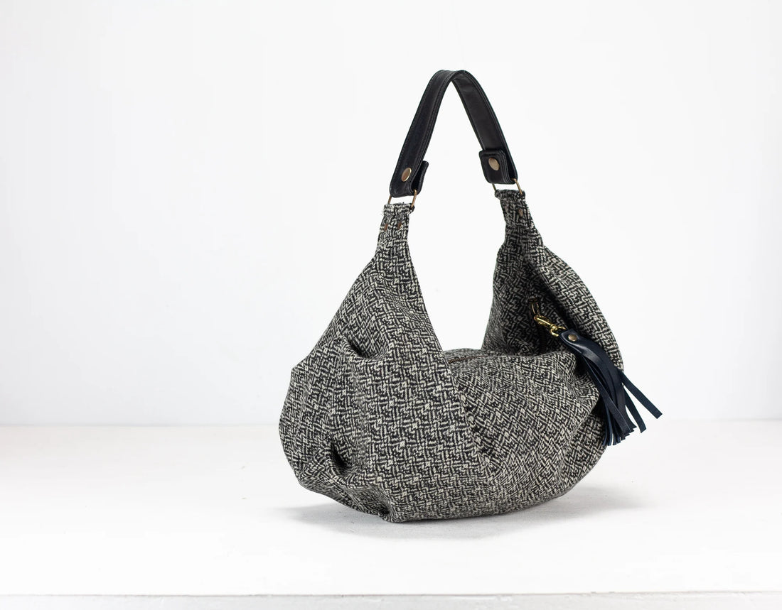 Gray textured handbag with a black strap on a white background