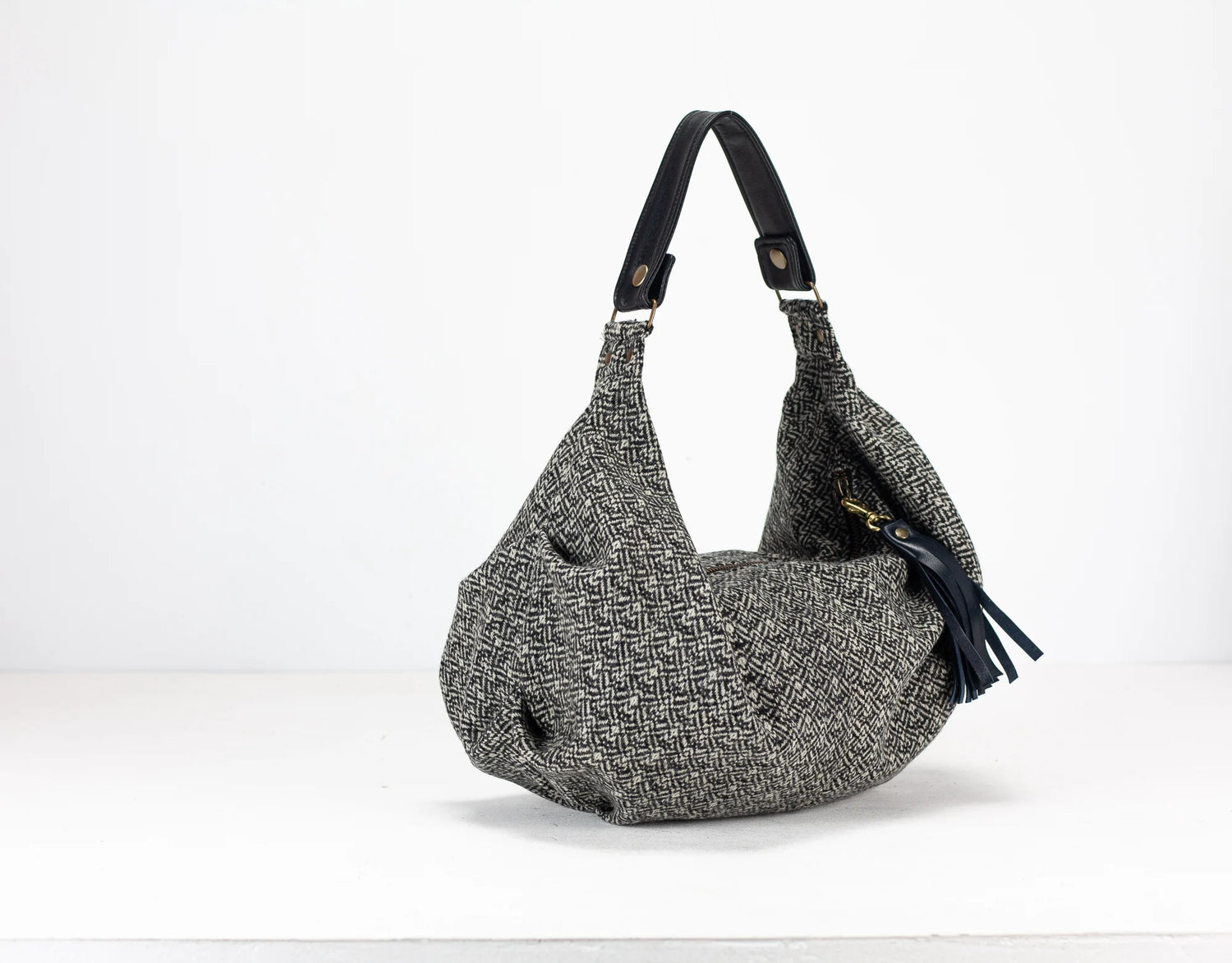 Gray textured handbag with a black strap on a white background