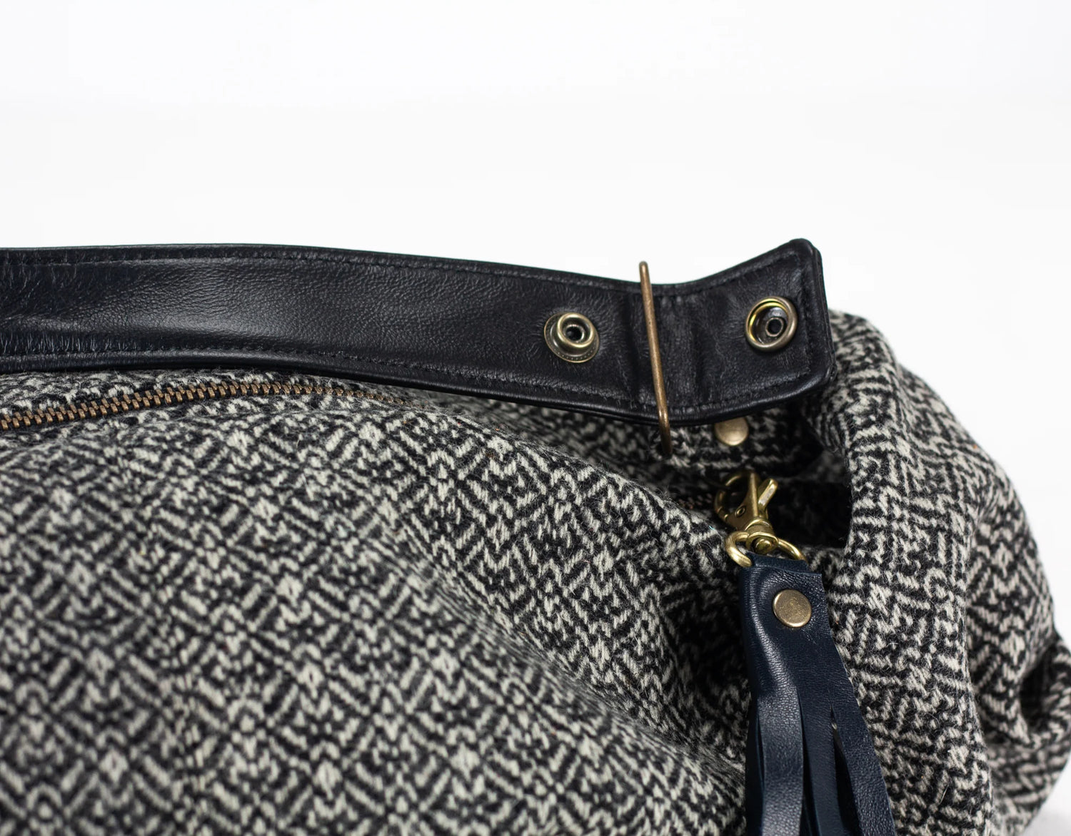 Close-up of a bag with black leather strap and gold hardware on a white background