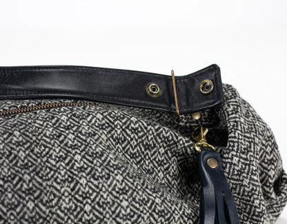 Close-up of a bag with black leather strap and gold hardware on a white background