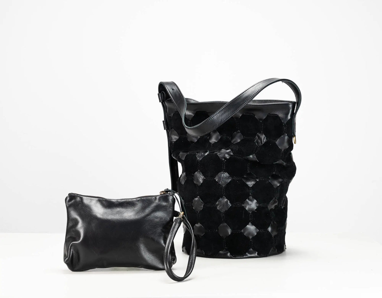 A black leather shoulder bag with a distinctive textured honeycomb pattern and a matching small black leather wristlet pouch, displayed on a clean white background.