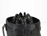 Black leather bucket bag with drawstring on a white background