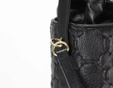 Black quilted handbag with a gold clasp on a white background