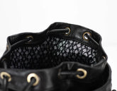 Close-up of a black leather drawstring bag with a patterned interior on a white background