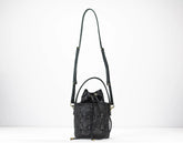 Black quilted handbag with a strap on a white background