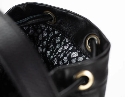 Close-up of a black leather drawstring bag with patterned interior.