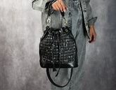 Person holding a black textured handbag against a gray background
