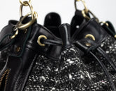 Close-up of a black drawstring bag with textured drawstrings and gold hardware.