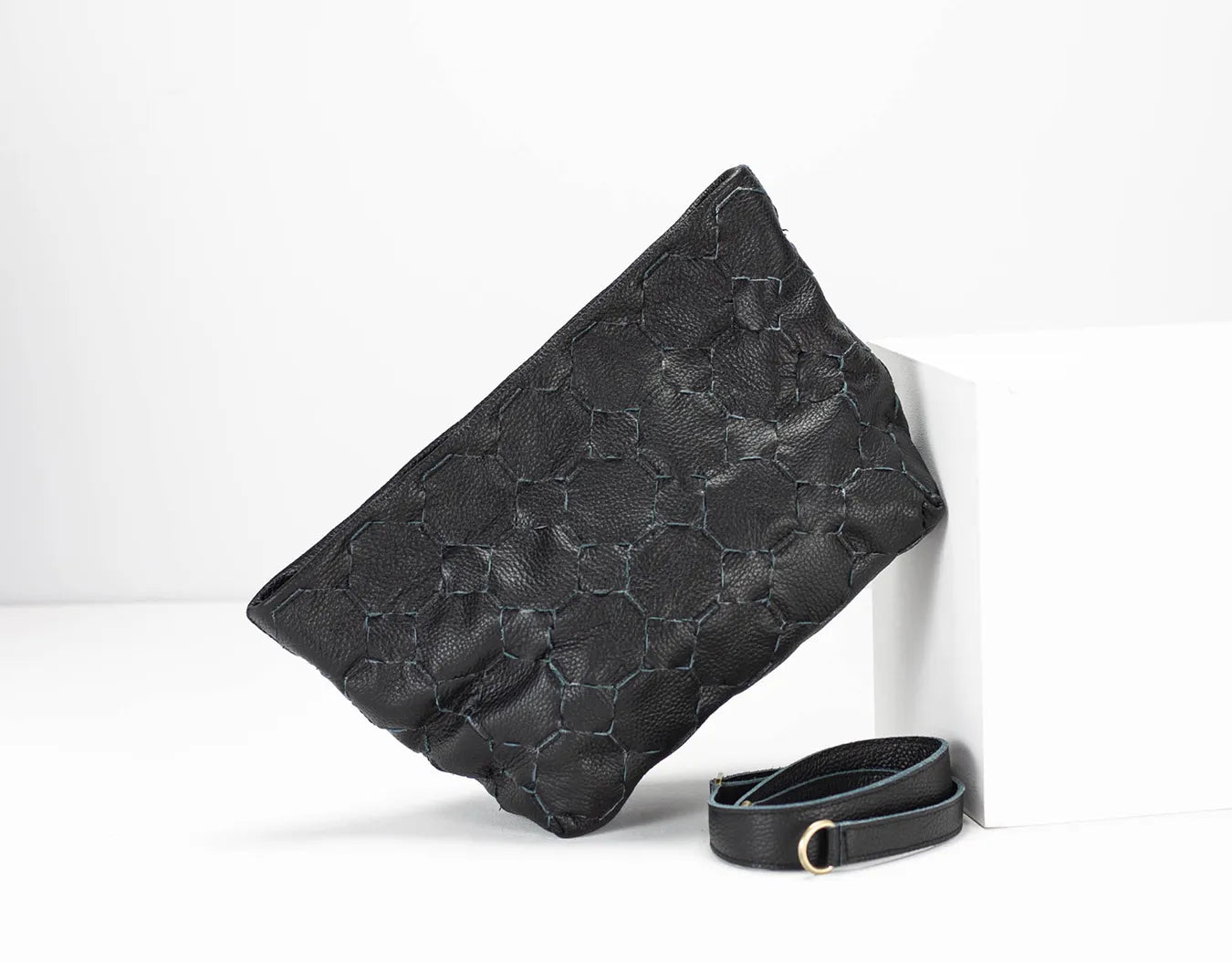 Black textured clutch bag with a matching belt on a white background