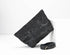 Black textured clutch bag with a matching belt on a white background