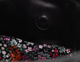 Close-up of a black leather product with floral fabric trim