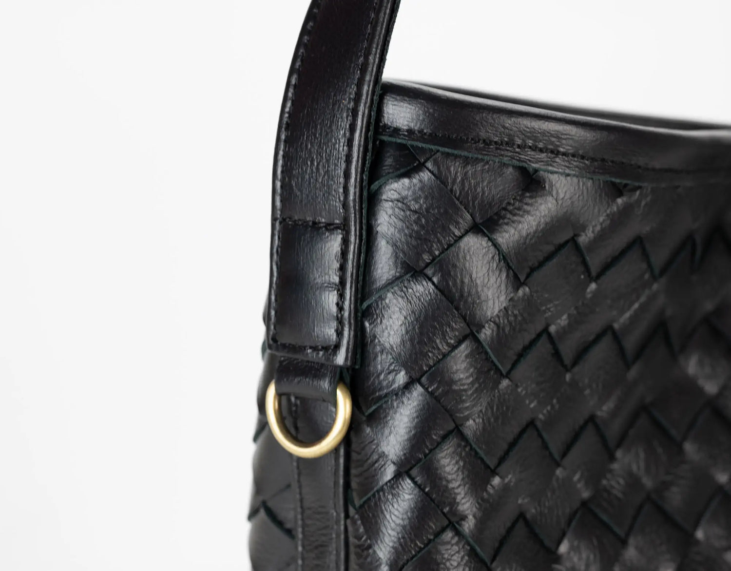 Close-up of a black woven handbag with a gold clasp on a white background
