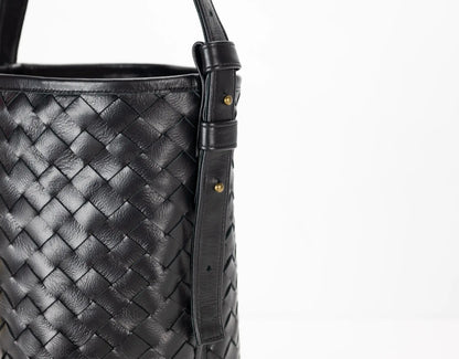 Black woven leather handbag with a strap on a white background