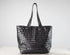 A black woven leather tote bag with two shoulder straps, displayed on a white surface against a light gray background.