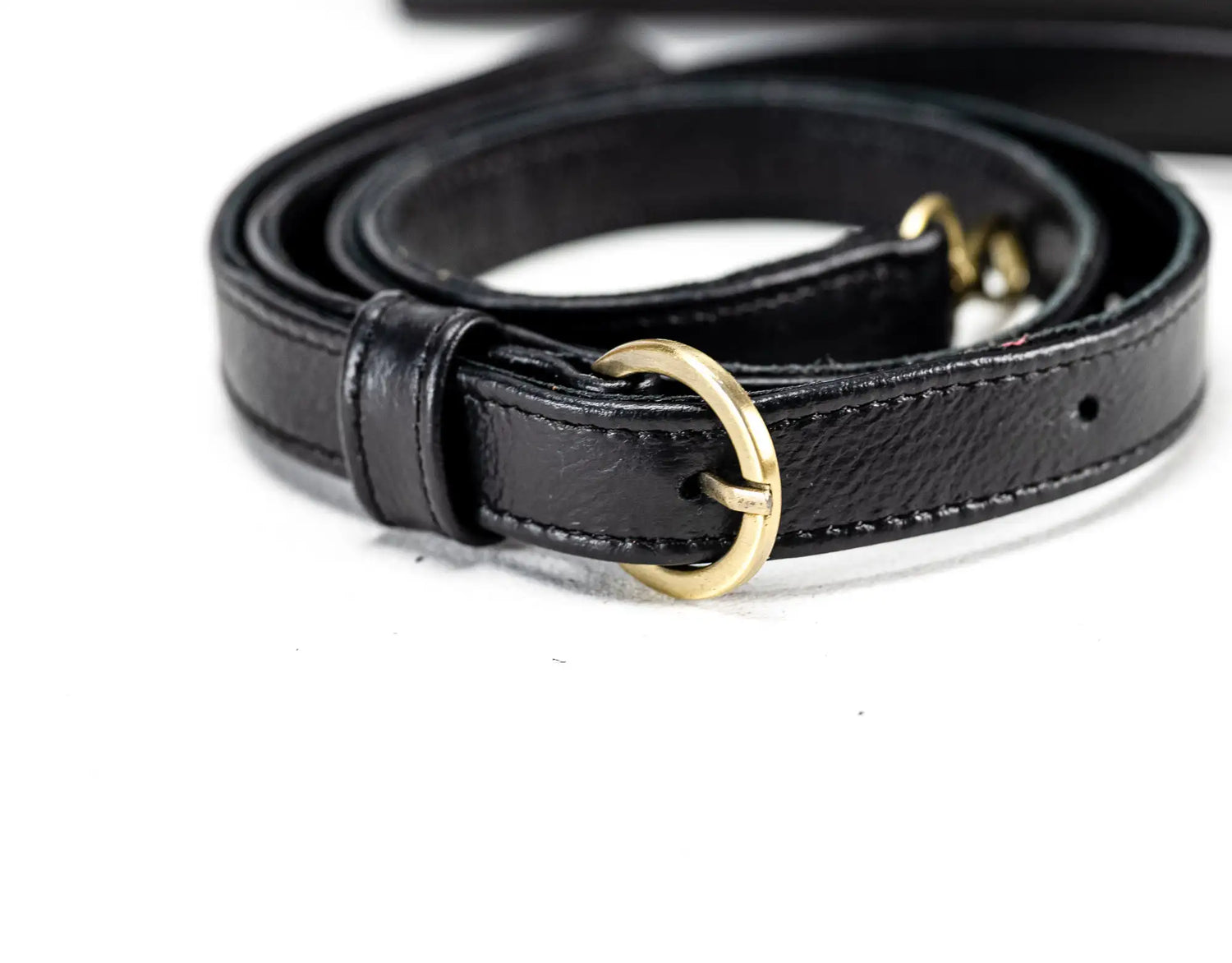 Black leather belt with a gold buckle on a white background