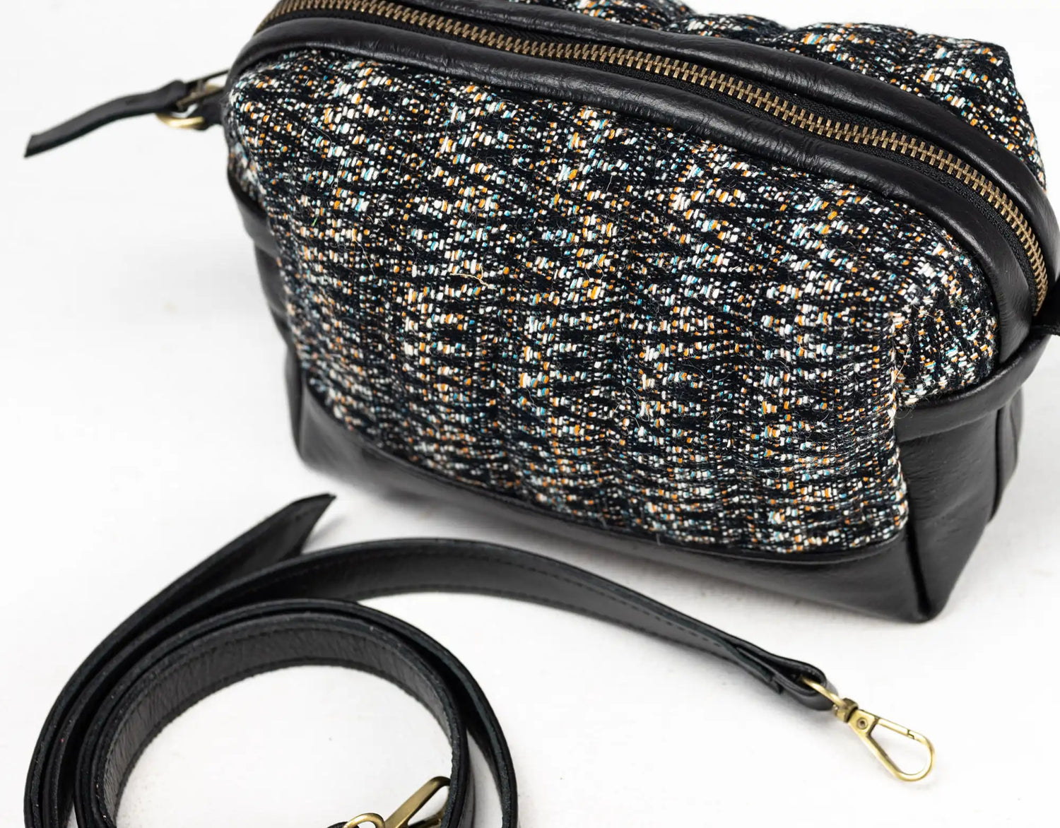 Black and gold patterned handbag with a strap on a white background