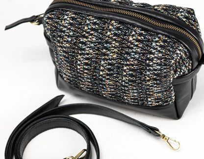 Black and gold patterned handbag with a strap on a white background