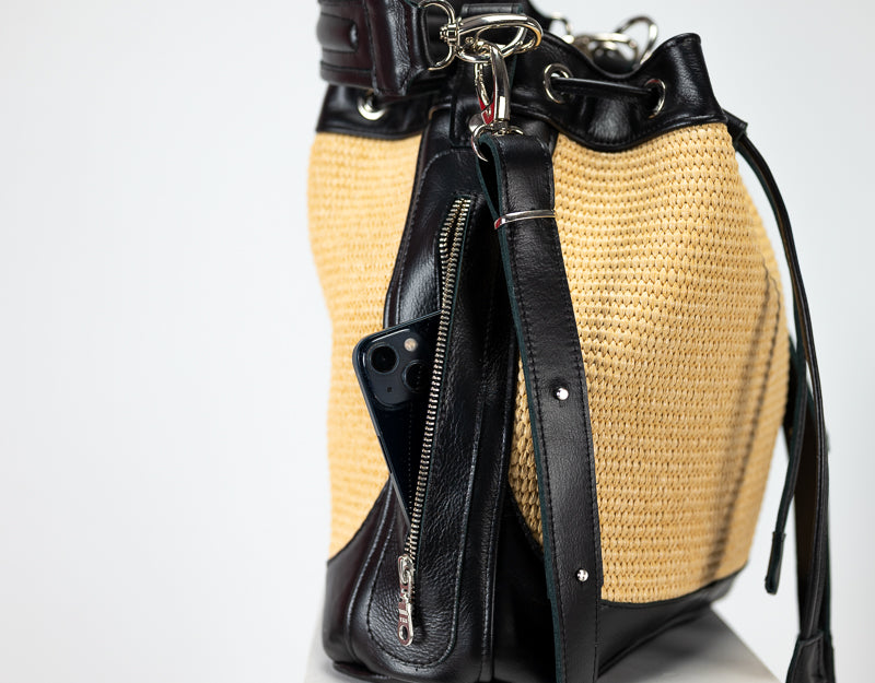 Woven handbag with black leather accents on a white background
