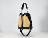 Handbag with straw and black leather design on a light gray background