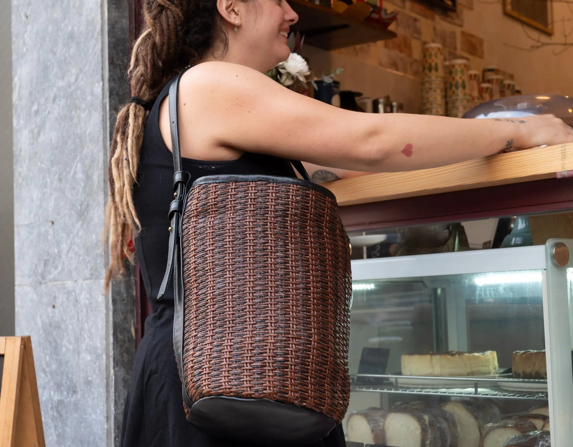 Person with a woven bag standing in a cafe.