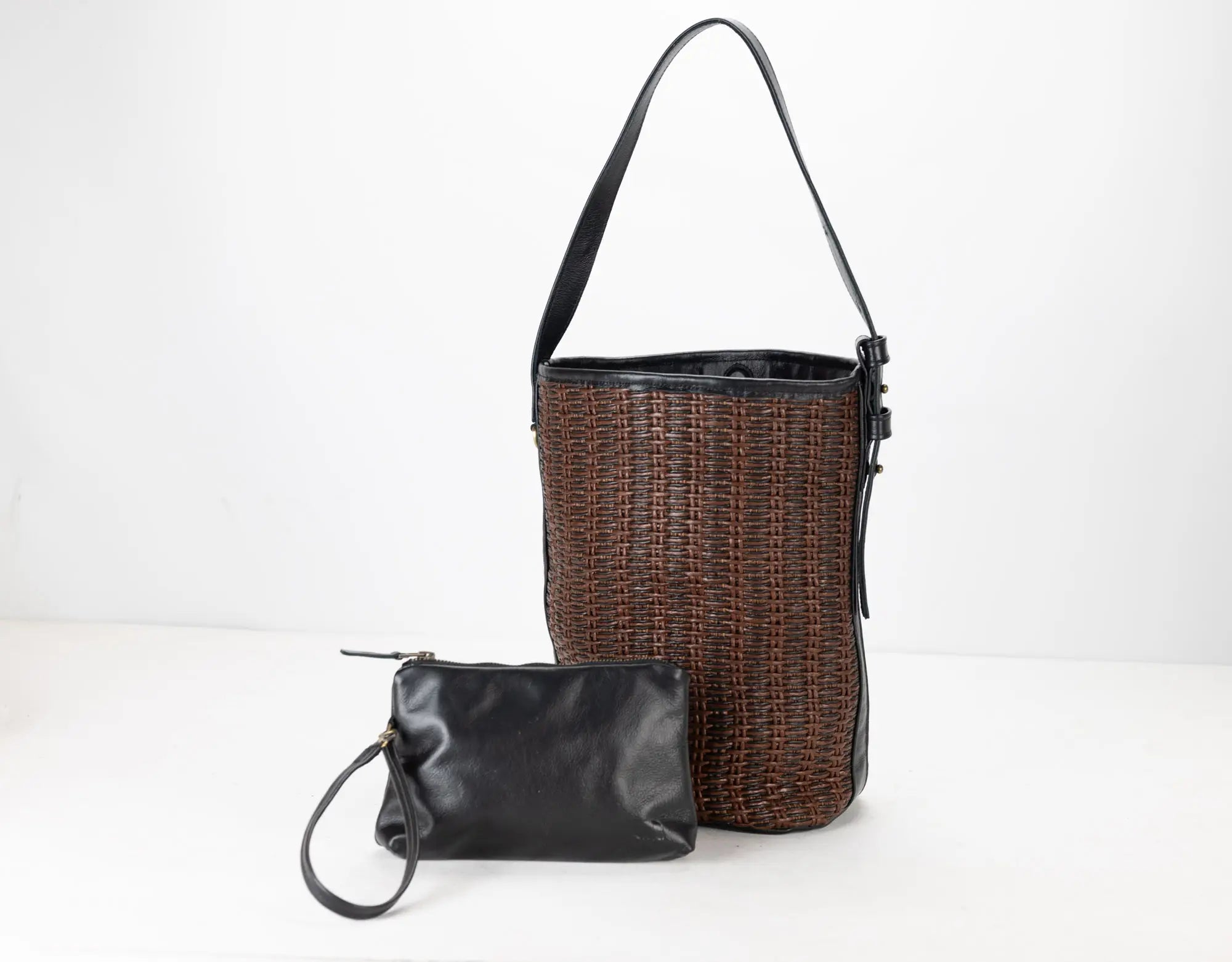 Woven bucket bag and black clutch on a white background
