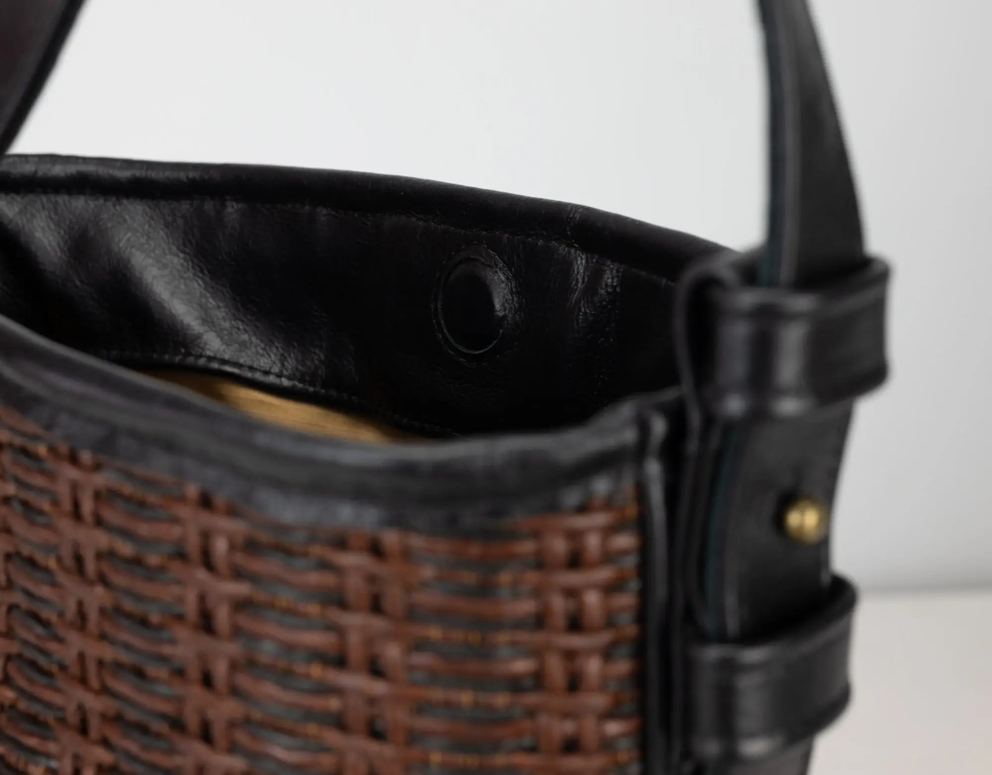 Close-up of a woven basket with black leather trim on a white background